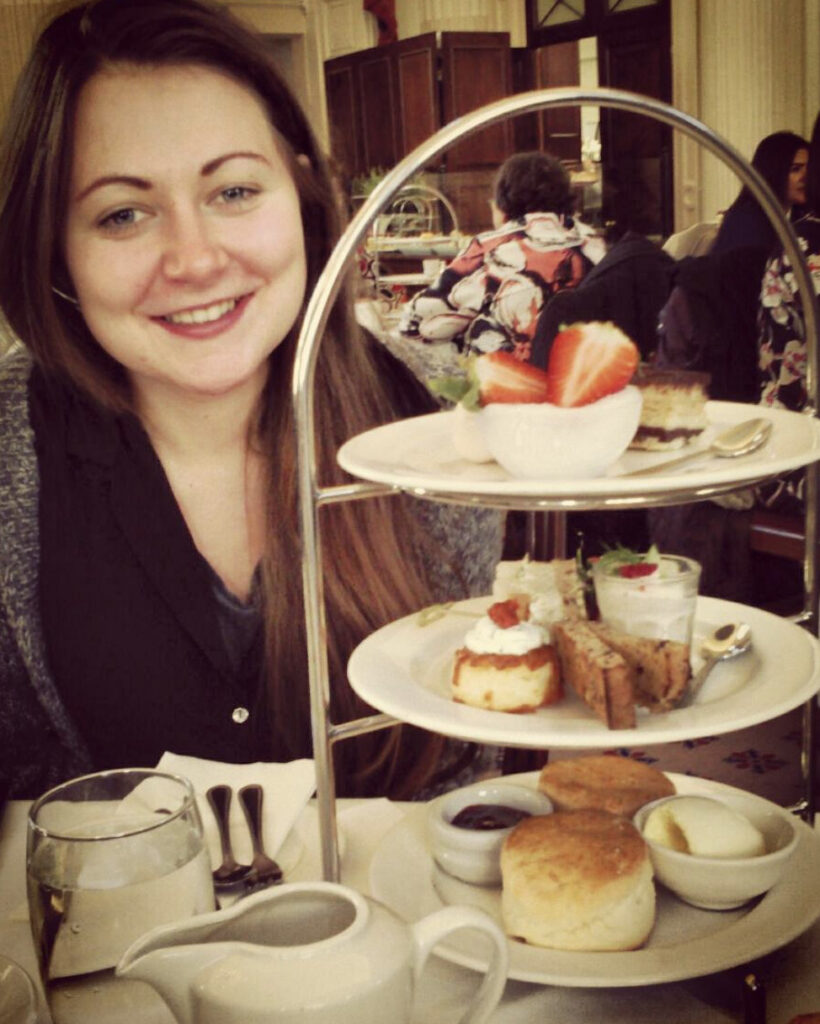 Girl sitting with a platter of sandwiches, cakes and pastries for afternoon tea.