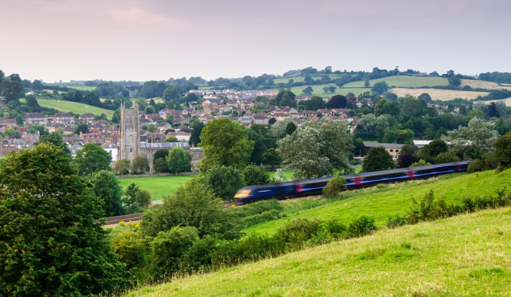 Bruton, England, United Kingdom - July 26, 2012: A First Great Western Intercity 125 high speed passenger train passes the church and town of Bruton, nestled in a valley under the rolling hills of Somerset.