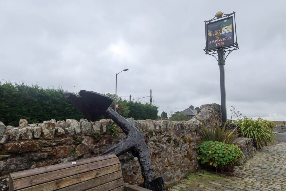 Jamaica Inn Sign, with clouds in the background and the fence of the inn in the foreground