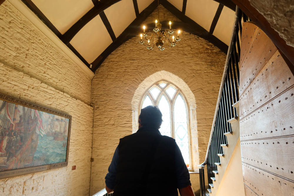 Man exploring a historic hall in a National Trust property. There is a window in the backgrond