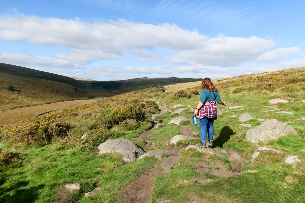 Girl walking on the moor with checked shirt tied around her waist and surrounding moorland