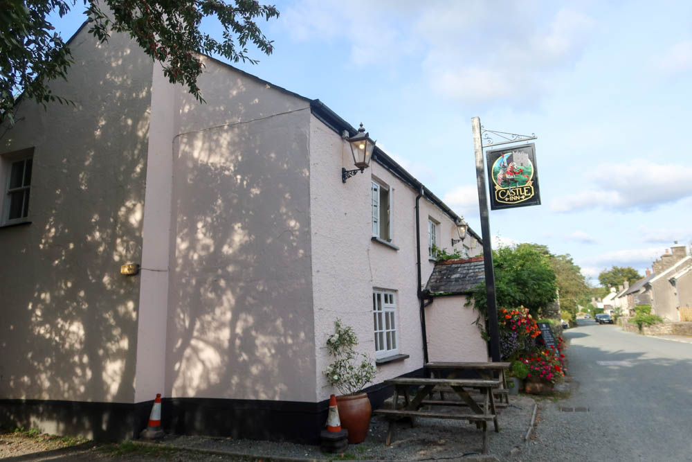 A view of the outside of a pub in Dartmoor, with the sign 'the castle inn' in the background. Drinking here is one of the best Lydford attractions. 