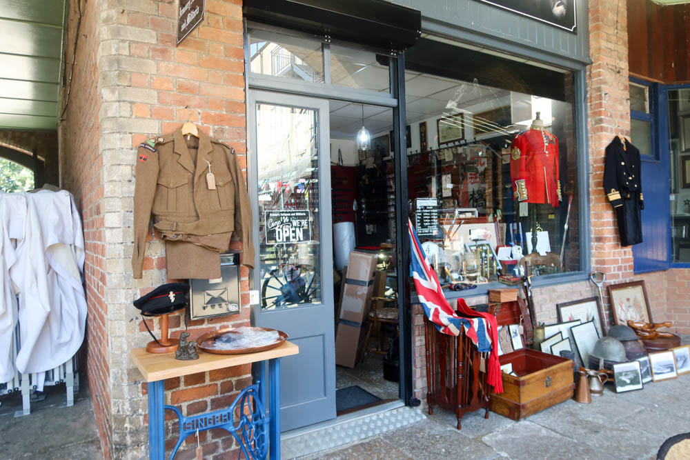 A quirky army gear shop in Tavistock. There's army memorabilia hanging outside like a brown jacket and other items.