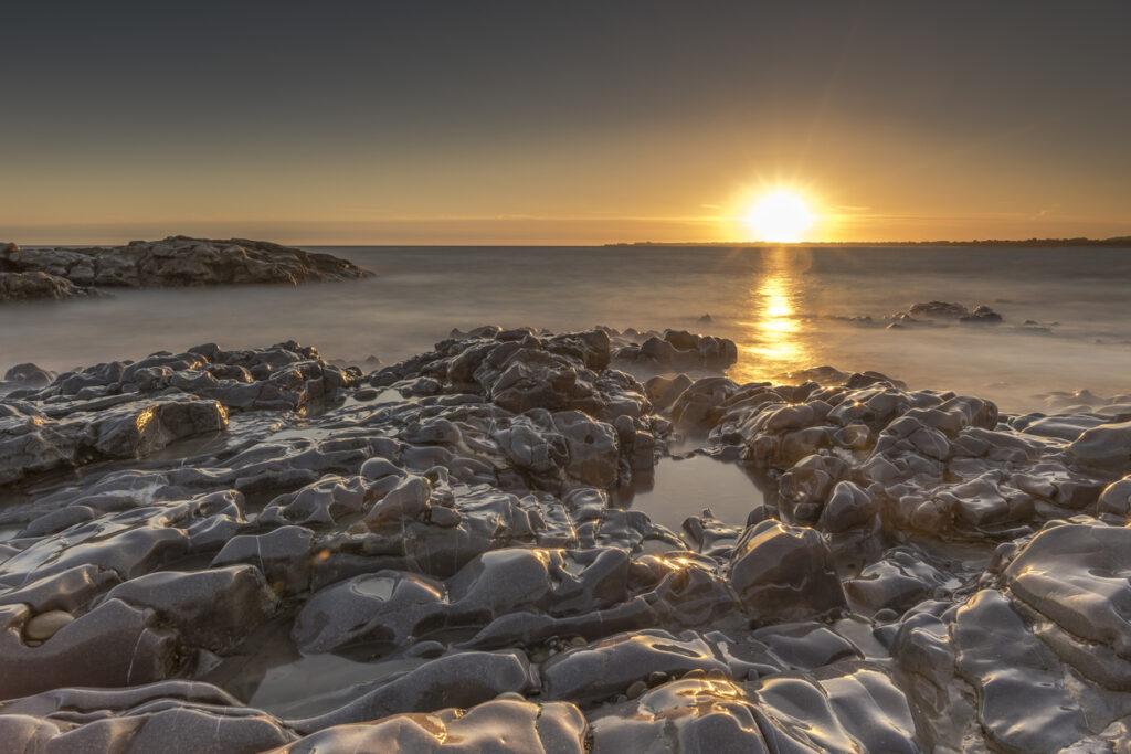 Sunset off the South Wales coast. Ogmore-by-Sea is a popular destination to swim and surf. A long shutter speed has been used to create a milky sea effect
