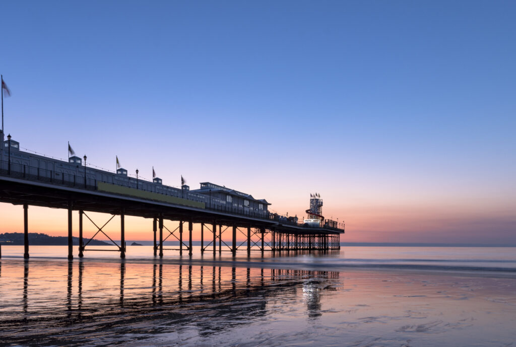 Paignton pier as the sun rises over Torbay, South Devon, UK.