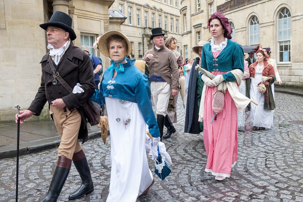 People in Jane Austen inspired clothes walking through the cobblestone streets of Bath