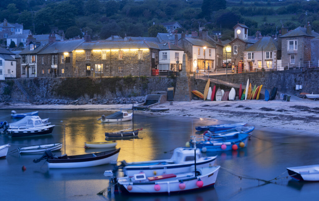 Twilight at Mousehole fishing village, where boats bob on the harbour, enjoy the twinkling lights 