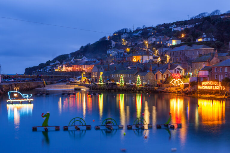 Beautiful display of Christmas Lights at Mousehole Harbour Cornwall England UK Europe. You can see the lights reflecting in the water and contrasting with the darkened village.