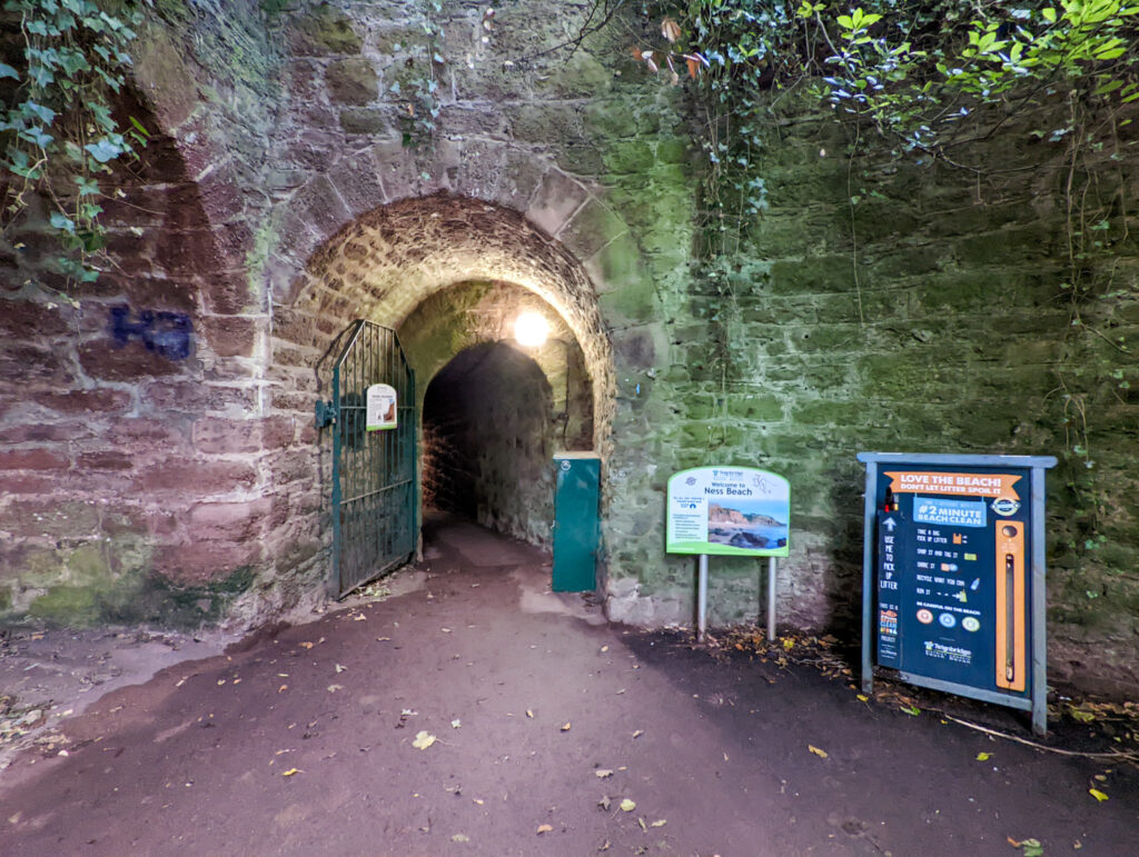 The entrance to Ness Cove beach through the smuggler's tunnel. This is right at the entrance, with brickwork on either side and signs to the right.