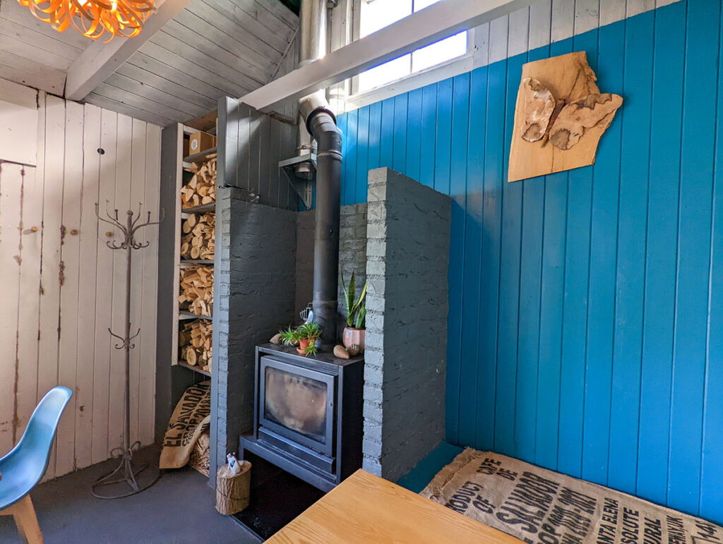 The rustic interior of cafe ODE, with blue paneling and a wood burner. 
