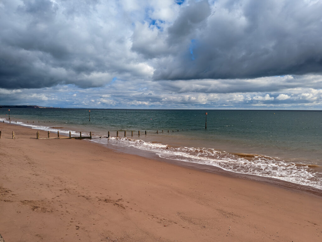 Teignmouth town beach, with golden sands, groynes and the blue water in the distance