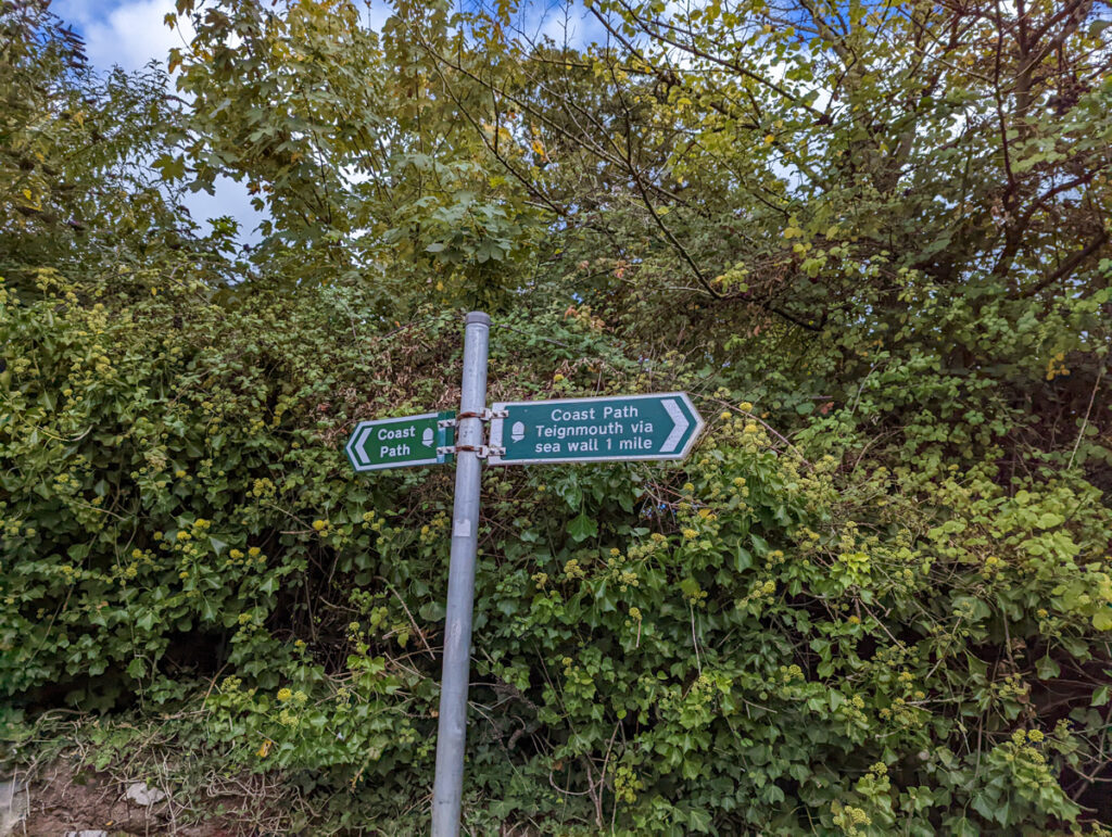 Sign indicating the south west coast path goes left and right. 