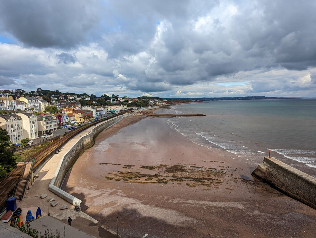 View of Dawlish beach, with houses behind the sea wall and the expansive sea stretching out in front.
