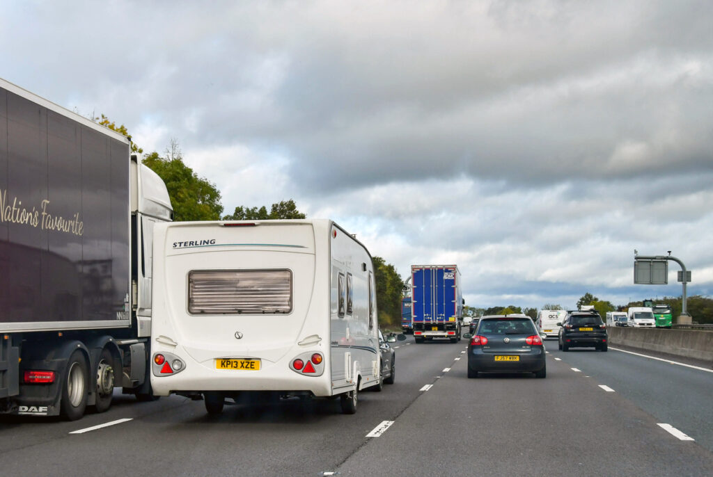 Midlands, England - October 2021: Car towing a caravan overtaking an articulated lorry on the M5 motorway