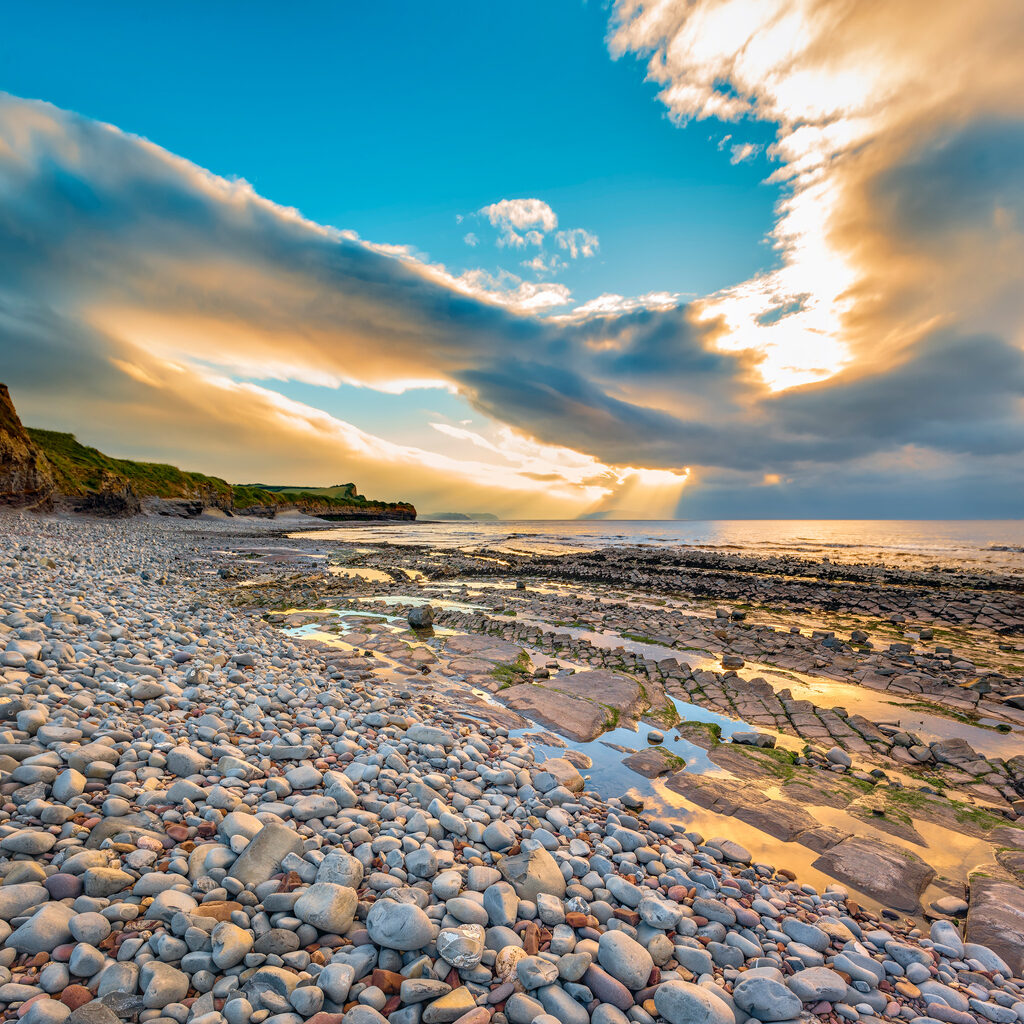 View of pebble Kilve beach at sunset. Copy space in blue sky
