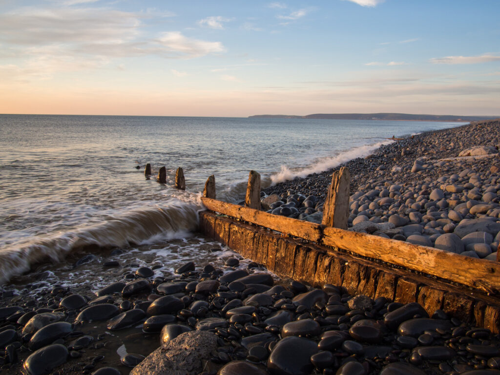 weathered beach groynes lit up by the setting sun at Westward Ho! in Devon , England