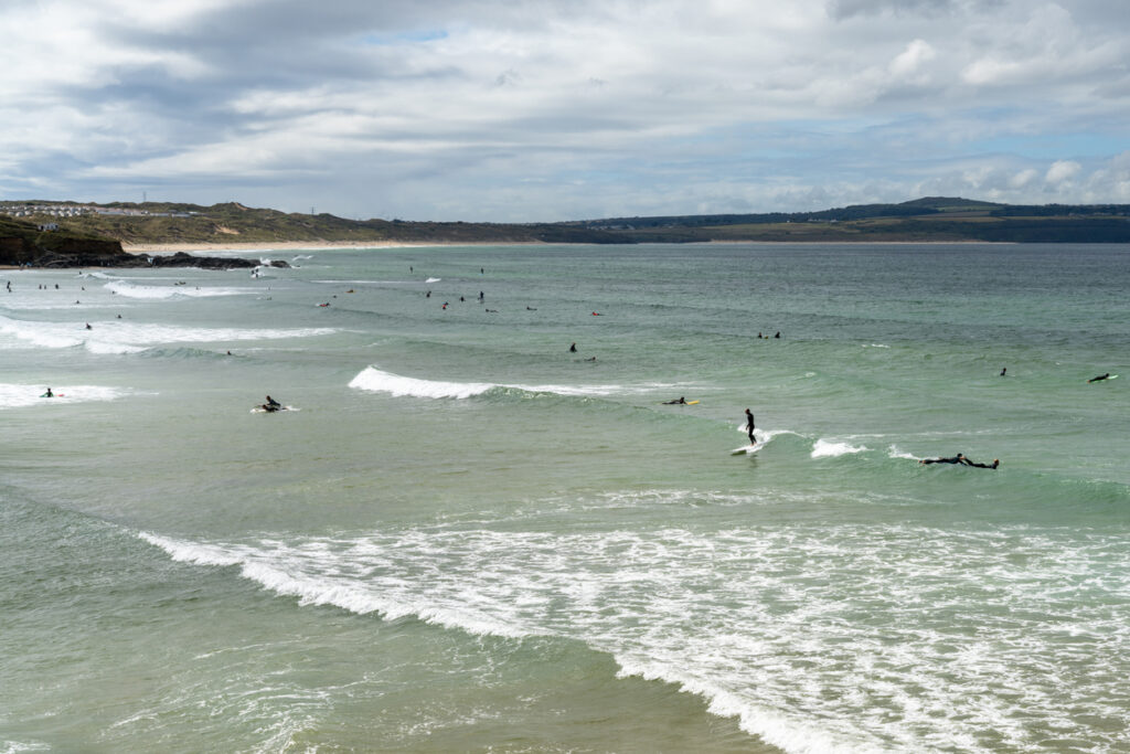 Gwithian, United Kingdom - 4 September, 2022: surfers enjoying good waves at Gwithian Beach in St. Ives Bay