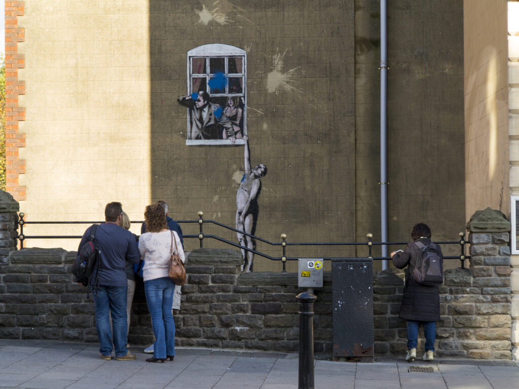 Bristol, UK - November 1, 2014: Viewed from Park Street, Naked Man - is an original example of Banksy grafitti artwork in Bristol which itself has been defaced by a paint bomb attack. It still attracts the attention of many visitors to Bristol.