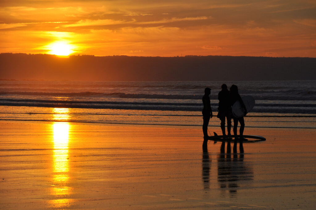 Surfers at sunset at Westward ho, North Devon, England