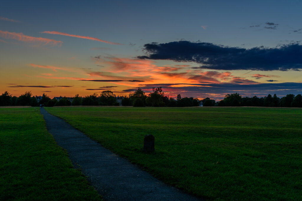 Sunset on Durdham Downs in Bristol, with walking path, tree lines, meadow, grassland, and colourful clouds.