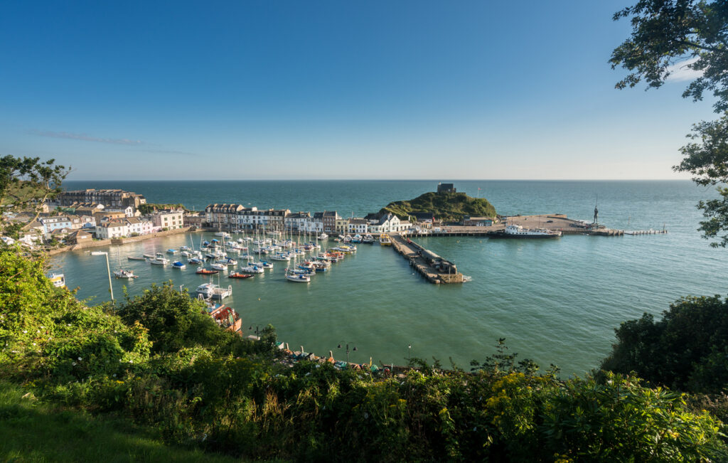 ILFRACOMBE, DEVON UK – JULY 24: Harbor at sunrise on 24 July 2017 in Ilfracombe, UK. The Damien Hirst statue Verity was erected in 2012