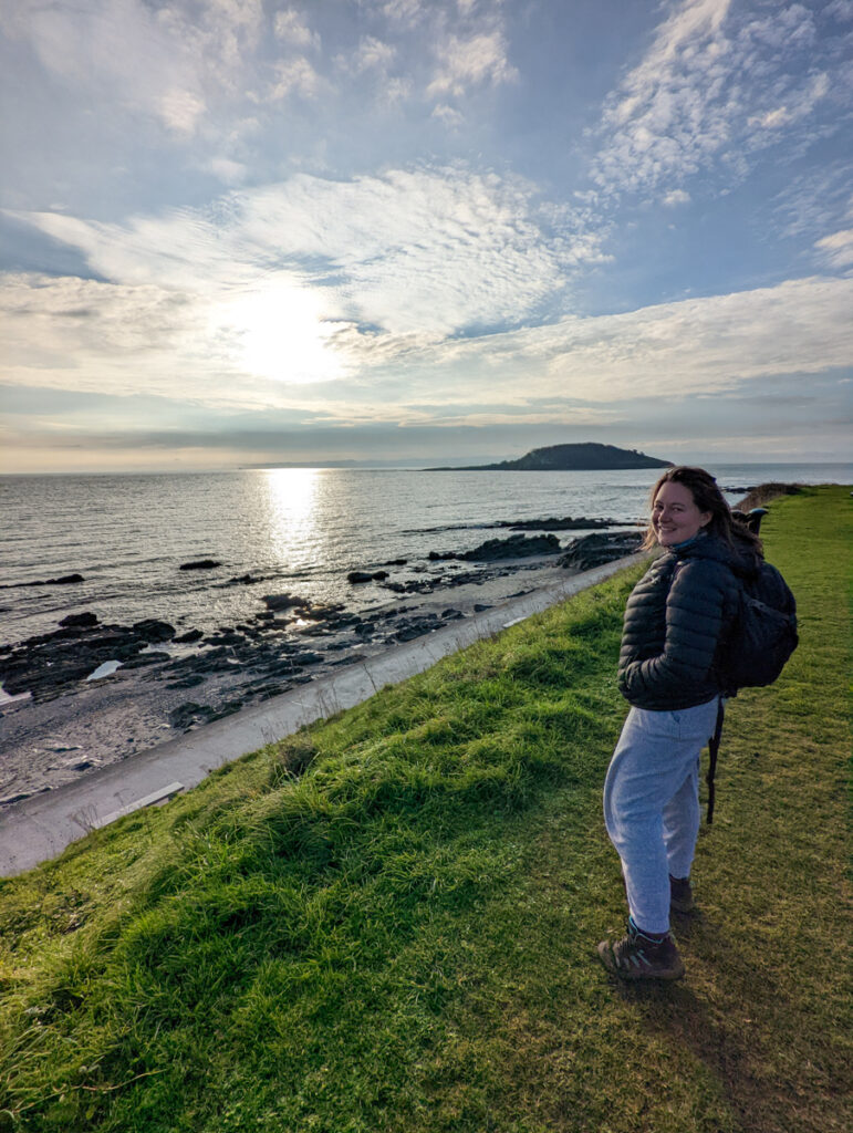 Girl standing on the South West Coast Path, looking out to Looe Island.