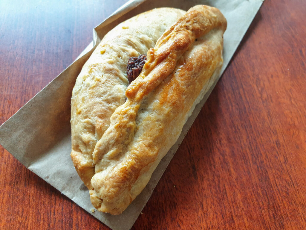 Mexican Cornish pasty made with beans and chilli, sitting on a wooden table.