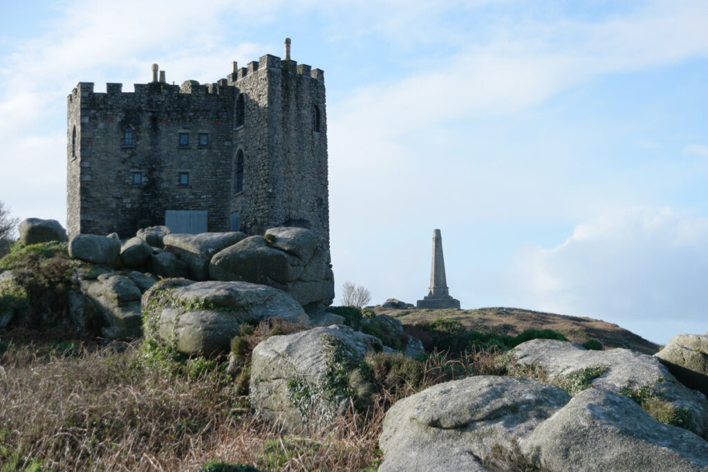 Carn Brea standing on top of the hill, with a monument and the castle. 