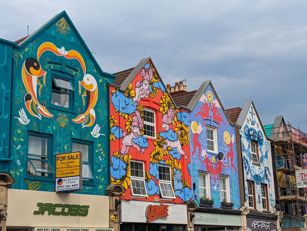 Terrace of houses, each with a mural on them, in Bristol.