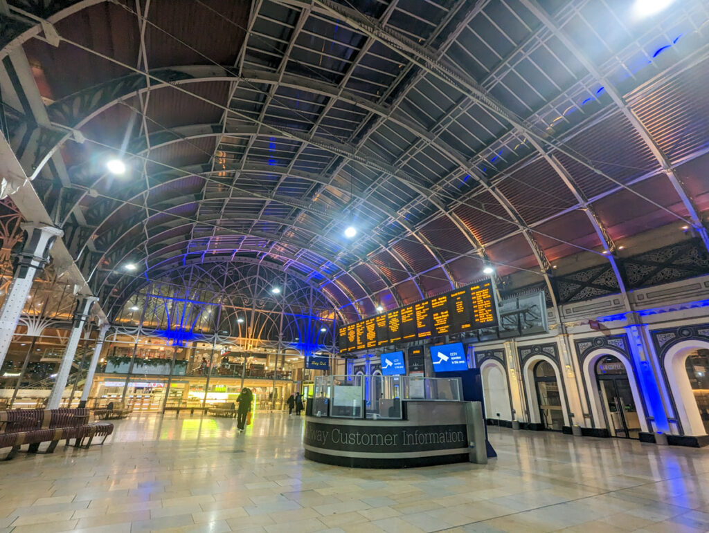 A view of Paddington Station with the information booth and signs with the different train times in the background.