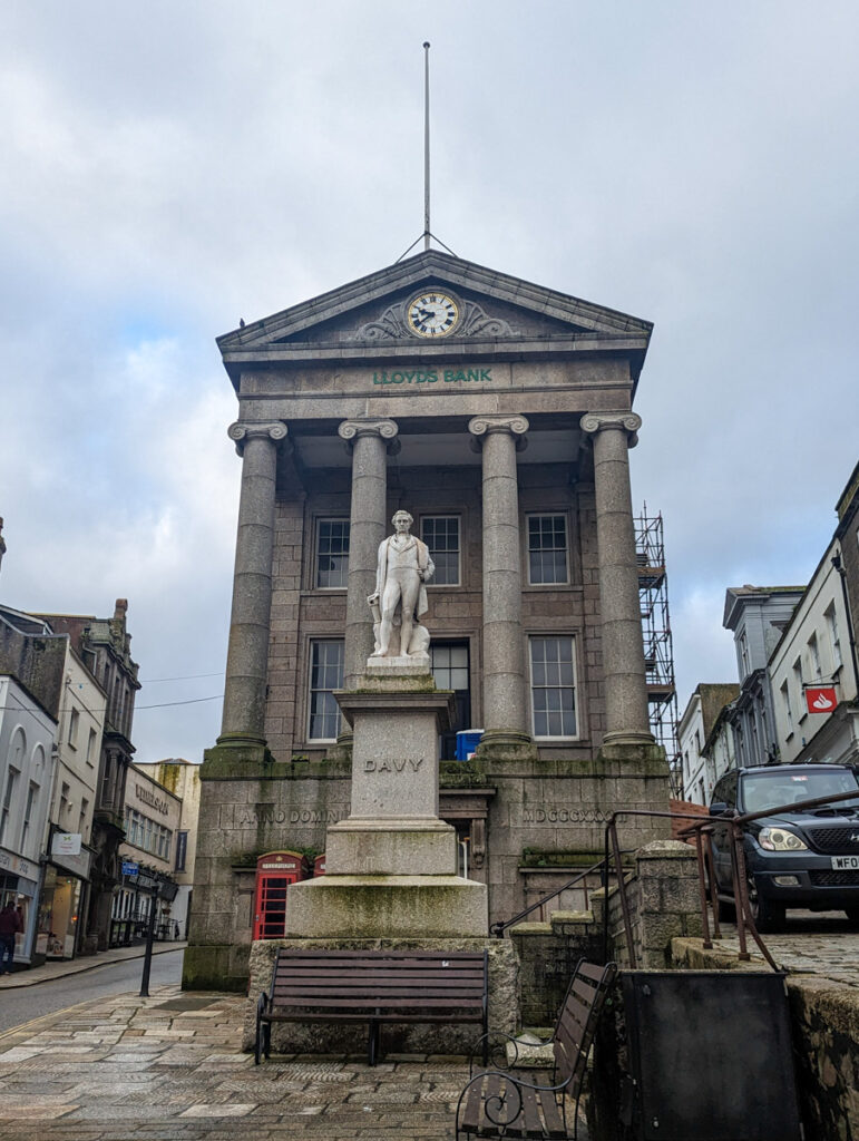 Historic bank building that's located in the old market house, with a statue in the foreground. 