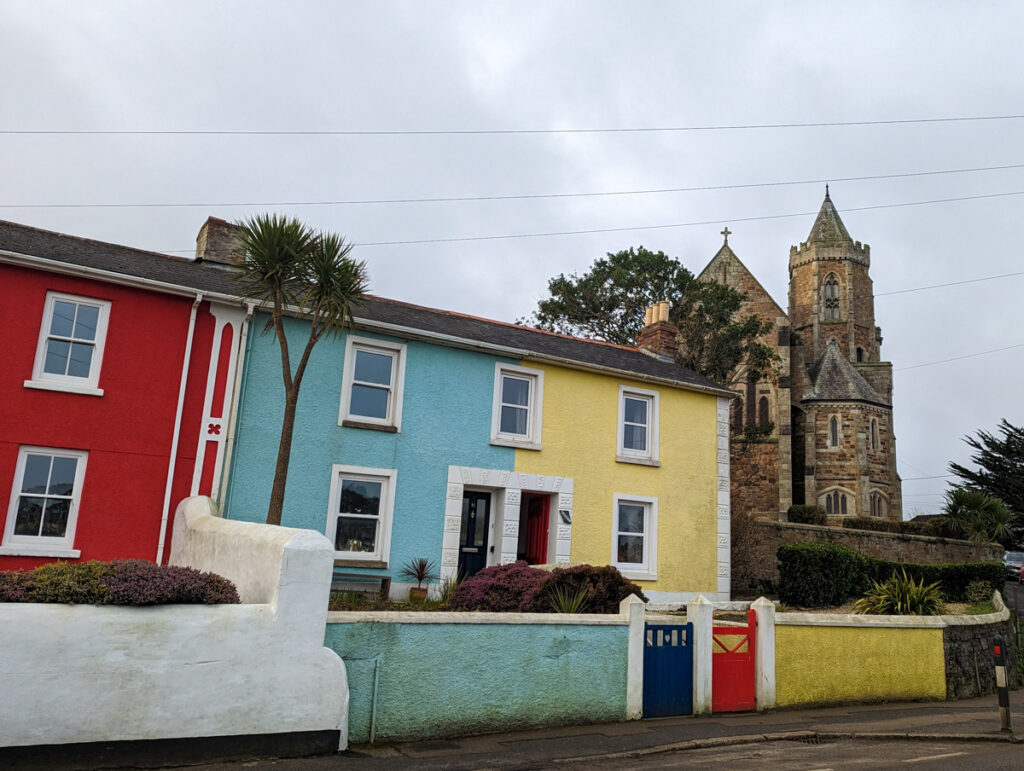 Colourful houses of Hayle in the foreground, with tall palm trees and a church in the background