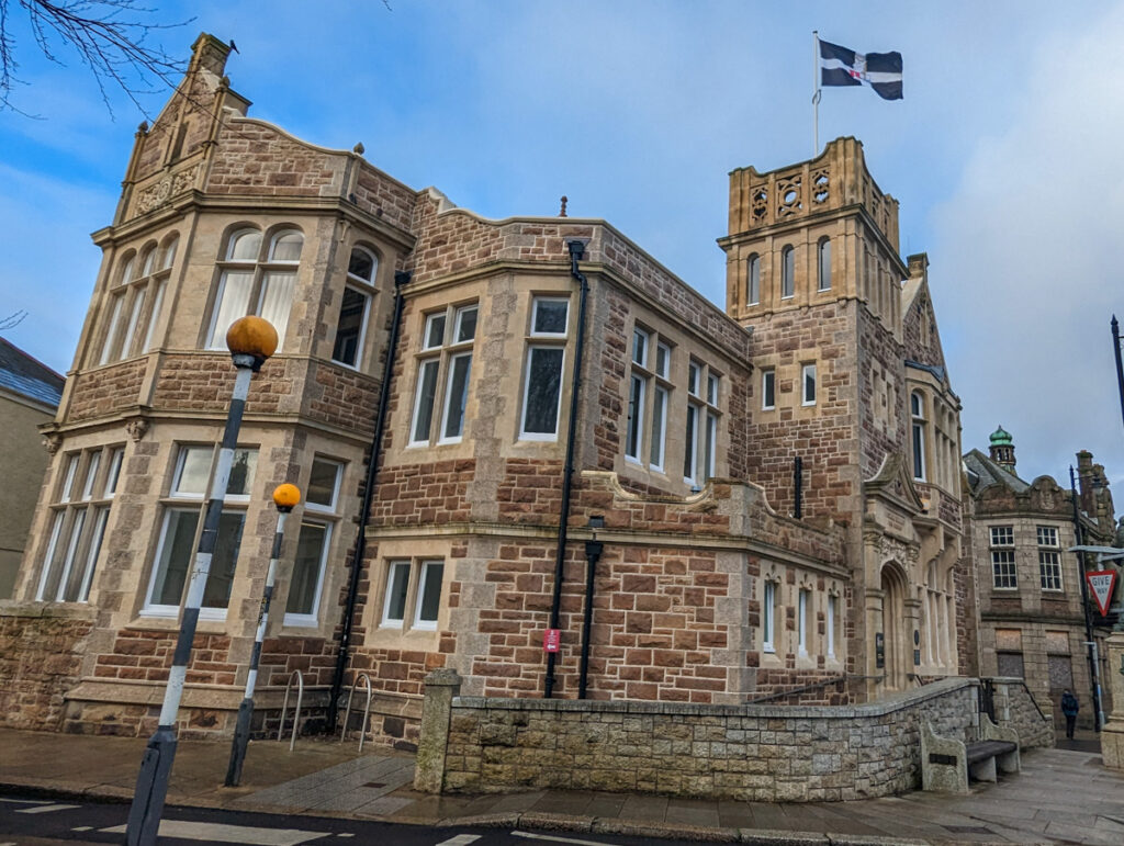 Granite town hall of Camborne, with Cornish flag flying proudly against the blue sky