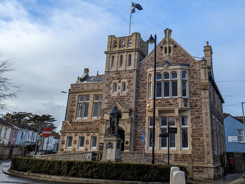 Historic building in Camborne with statue in front.