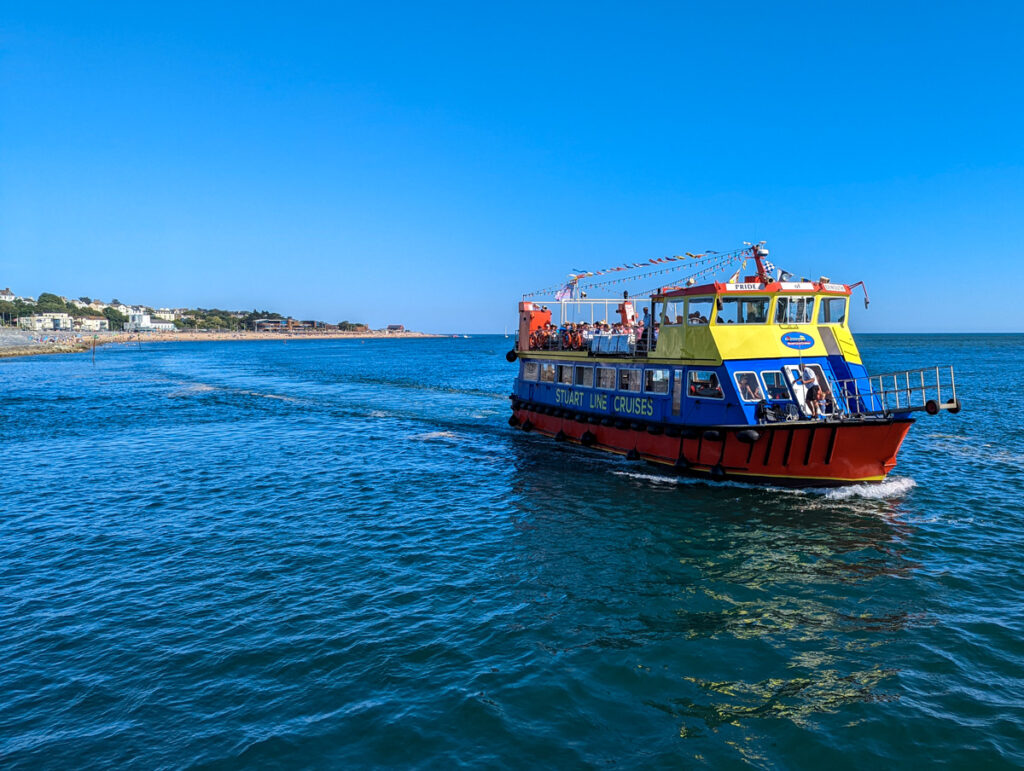 Yellow, blue and red Stuart Line Cruises boat on the bright blue water sailing to the estuary 