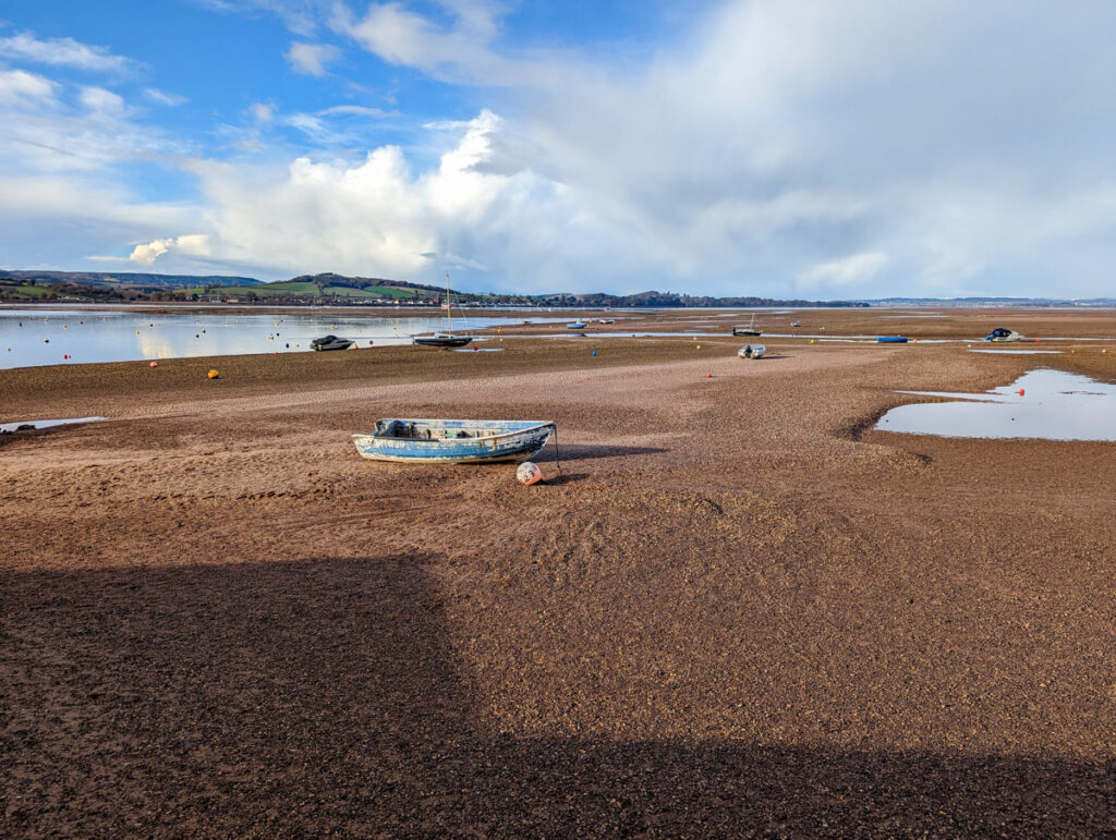 Exmouth beach, with light cloud coverage, the sea at one end and boats on the sand.