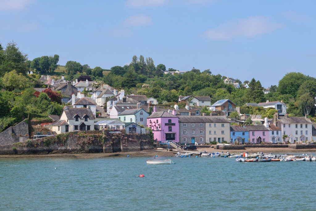 The pretty village of Dittisham with bright coloured buildings and the river infront.