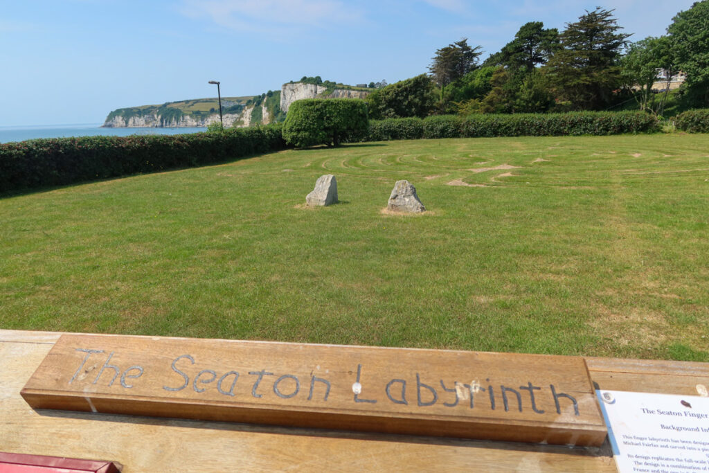 The Seaton Labyrinth with view over to the cliffs. Sign of the Seaton Labyrinth is in the foreground.