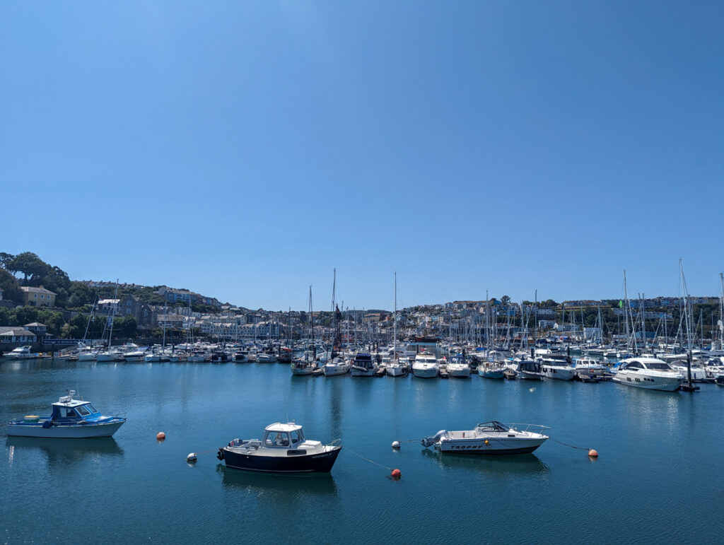 Boats bobbing on the calm blue water of Brixham Harbour.