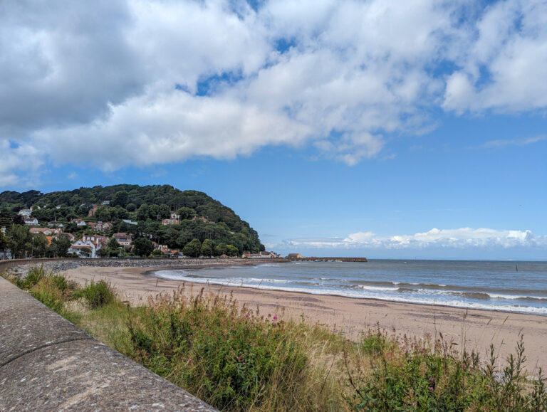 A view of Minehead, with the headland in the background and beach in the foreground.