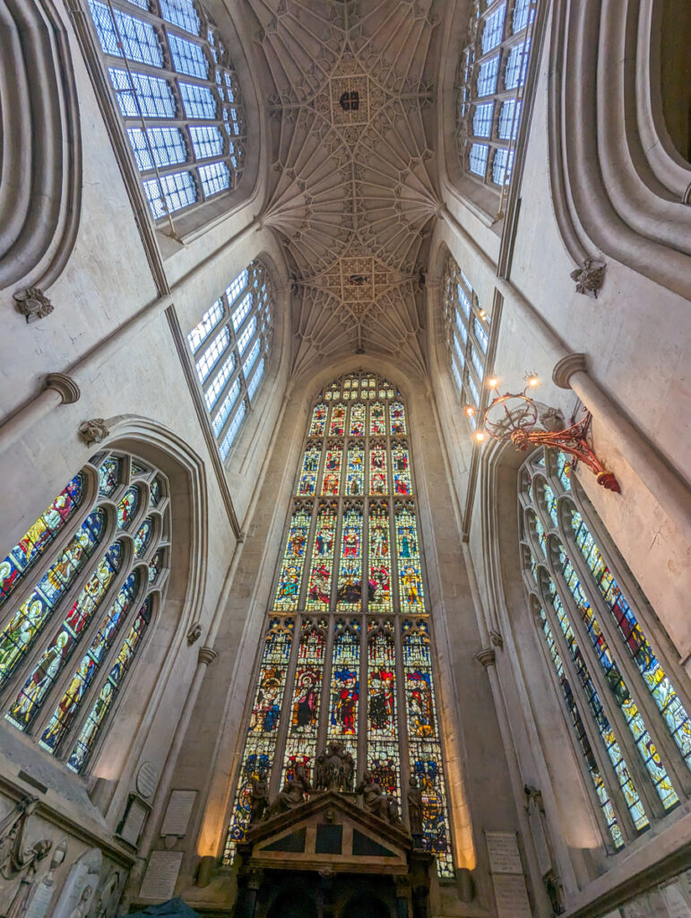 Expansive interior view of a cathedral's nave, with high vaulted ceilings, grand stained glass windows, and a detailed rood screen, embodying the grandeur of Gothic architecture.