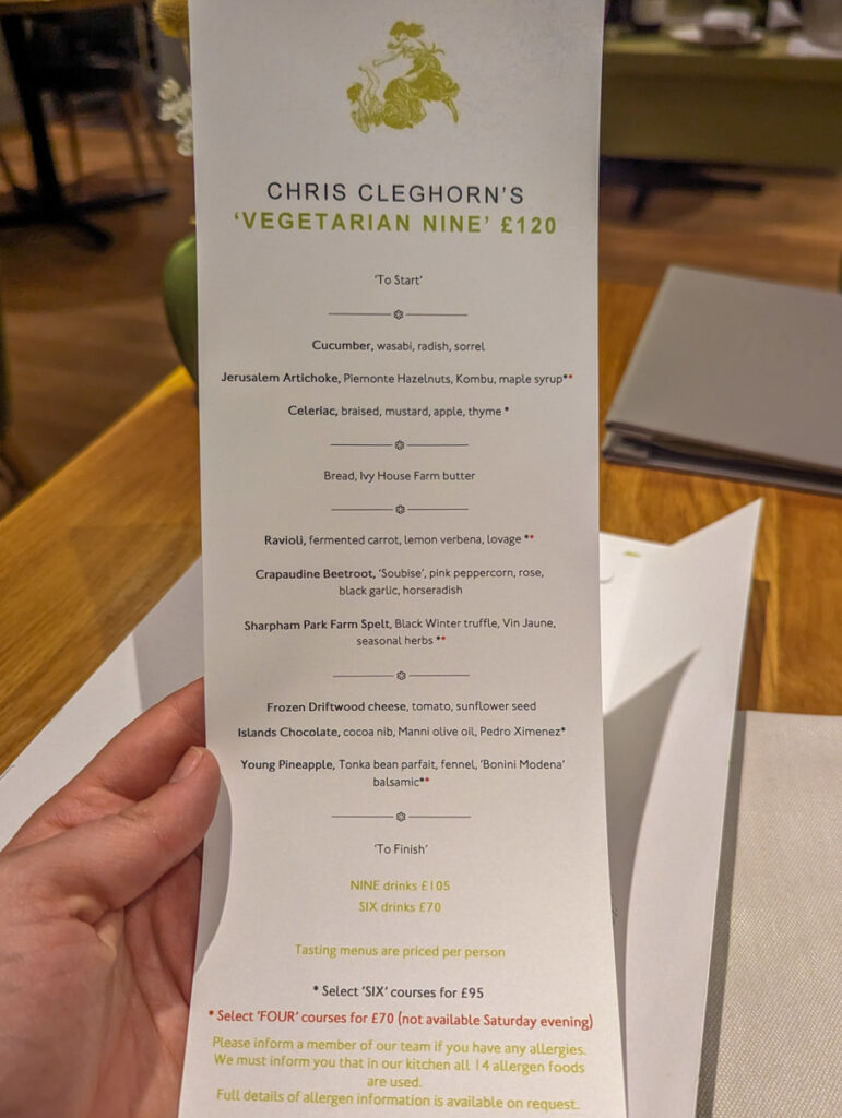 A vegetarian tasting menu held by a person in a dining setting, offering a selection of gourmet dishes, emphasizing the restaurant's high-end culinary experience