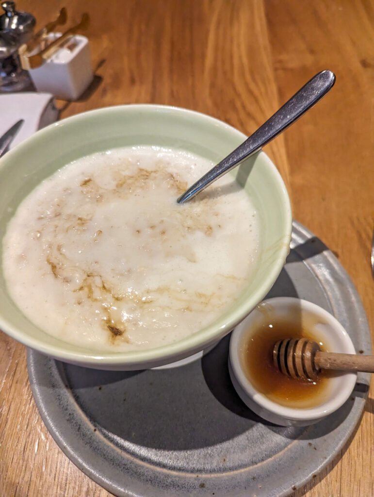 A comforting bowl of porridge served with a drizzle of honey on a rustic wooden table, suggesting a warm start to a cold morning.